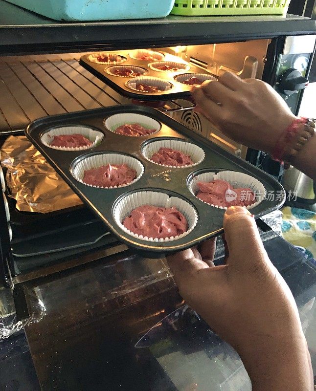 红丝绒纸杯蛋糕/不粘松饼托盘/蛋糕被放在热烤箱，家庭烘焙照片